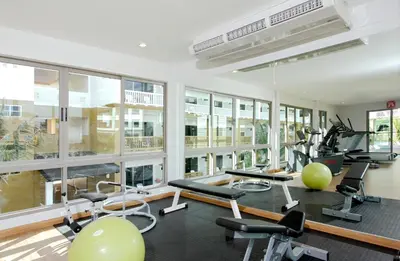 a gym with a lot of exercise equipment and windows at Kata Sea Breeze Resort - SHA Plus in Kata Beach
