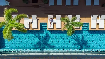 a woman standing in front of a hotel sign with palm trees at The Marina Phuket Hotel in Patong Beach