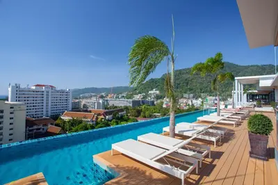 a hotel swimming pool with lounge chairs and palm trees at The Marina Phuket Hotel in Patong Beach