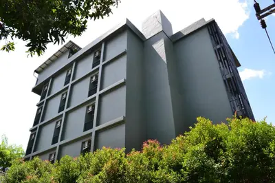 a tall grey building with trees in front of it at Ritsurin Boutique Hotel - โรงแรมริทสุริน บูติค in Phuket Town