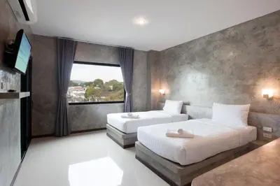 a hotel room with two beds and a television at Ritsurin Boutique Hotel - โรงแรมริทสุริน บูติค in Phuket Town