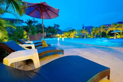 a swimming pool with chairs and an umbrella next to a resort at PS Hill Resort Phuket Patong - SHA Plus in Patong Beach