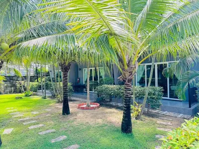 two palm trees in front of a building at Marisa Garden Bungalow in Bang Tao Beach