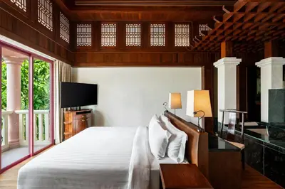 a bedroom with a white bed and a tv at Centara Grand Beach Resort Phuket in Karon Beach