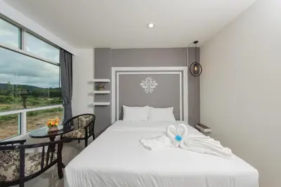 a bedroom with a bed and a table and a window at Vacation Time House in Nai Yang Beach