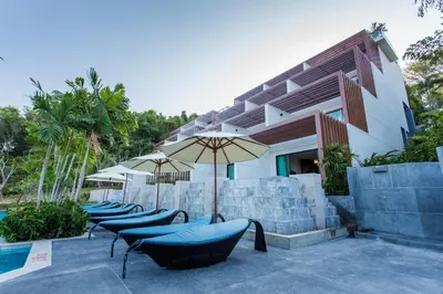 a row of chairs and umbrellas next to a pool at Chalong Chalet Resort in Chalong