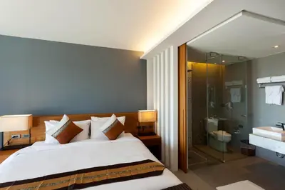 a bedroom with a large bed and a bathroom at Chalong Chalet Resort in Chalong