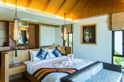 a bedroom with a large bed and a bench at Chalong Chalet Resort in Chalong