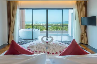 a bedroom with a large window with a bath tub at Chalong Chalet Resort in Chalong