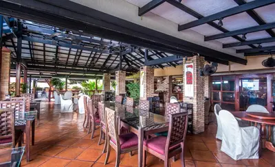 a restaurant with tables and chairs in a room at Bougainvillea Terrace House in Kata Beach