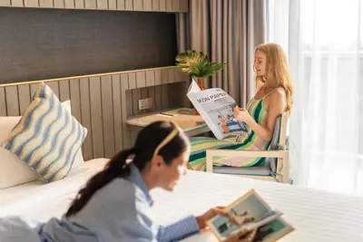 two women sitting at a table in a hotel room at Hotel IKON Phuket - SHA Extra Plus in Karon Beach