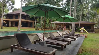 a row of lounge chairs with umbrellas next to a pool at Melina Beach Front Bungalows in Tha Lane Bay