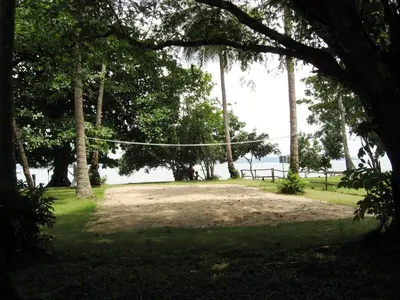 a hammock in a park with trees and the water at Melina Beach Front Bungalows in Tha Lane Bay