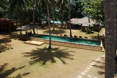 a swimming pool with people sitting under umbrellas at Melina Beach Front Bungalows in Tha Lane Bay