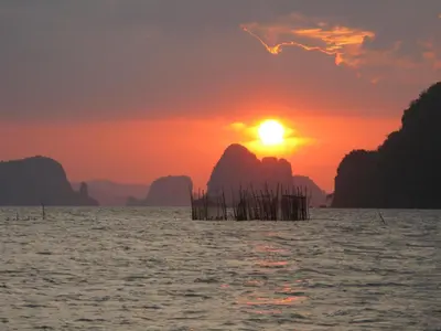 a sunset over the water with mountains in the background at Melina Beach Front Bungalows in Tha Lane Bay