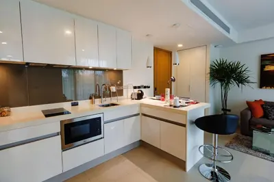 a kitchen with white cabinets and a black stool at Oceanstone by Holy Cow, 2-BR, 60 m2, tree view in Bang Tao Beach