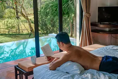 a man laying on a bed reading a book at VILLA Chacha VILLA Coco RESORT APOLLONIA in Ko Yao Noi