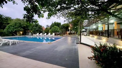 a swimming pool with white chairs next to a building at Supsangdao Resort in Ao Nang Beach