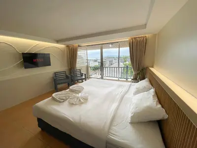 a bedroom with a large white bed with a balcony at Ben's House in Ao Nang Beach