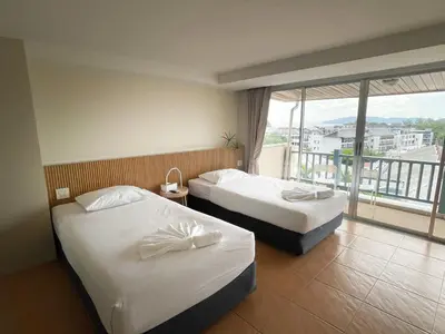two beds in a hotel room with a balcony at Ben's House in Ao Nang Beach