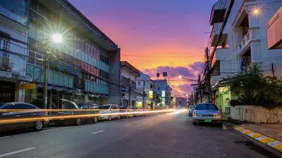 a city street at sunset with cars driving down the street at The Neighbors Hostel in Phuket Town