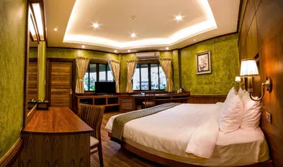 a hotel room with a bed and a desk and a desk at Naiyang Park Resort - SHA Extra Plus in Nai Yang Beach