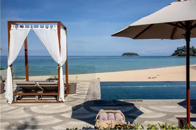 a pool with an umbrella and chairs and the beach at The Shore At Katathani - Adult Only - SHA Extra Plus in Kata Beach