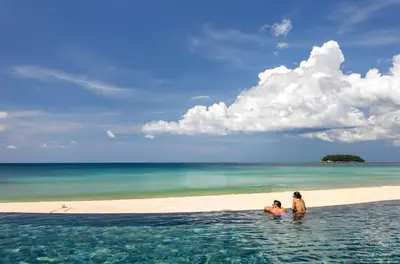 two people sitting in the water on a beach at The Shore At Katathani - Adult Only - SHA Extra Plus in Kata Beach