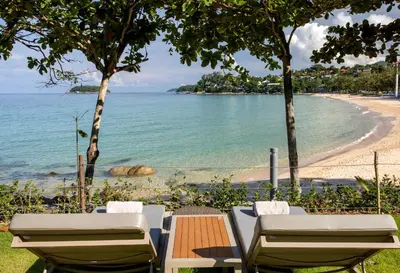 a view of a beach with two chairs and a table at The Shore At Katathani - Adult Only - SHA Extra Plus in Kata Beach