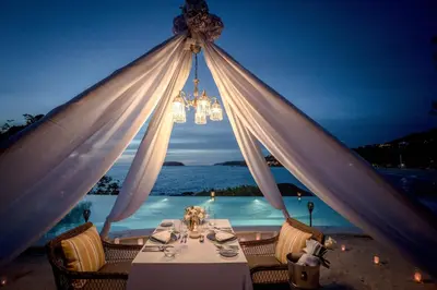a dining table with a chandelier in front of a pool at The Shore At Katathani - Adult Only - SHA Extra Plus in Kata Beach