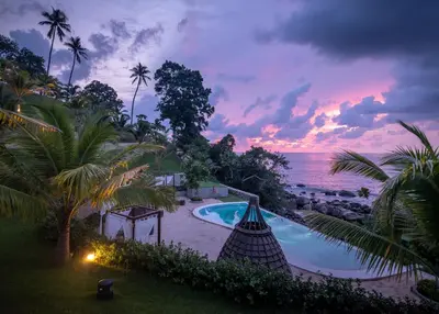 a view of a pool and the ocean at sunset at The Shore At Katathani - Adult Only - SHA Extra Plus in Kata Beach