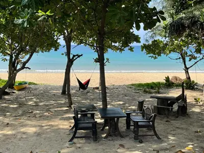 a hammock and tables and chairs on a beach at Beach house by Rose massage in Nai Thon Beach