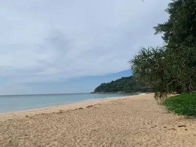 a sandy beach with trees and the ocean at Beach house by Rose massage in Nai Thon Beach