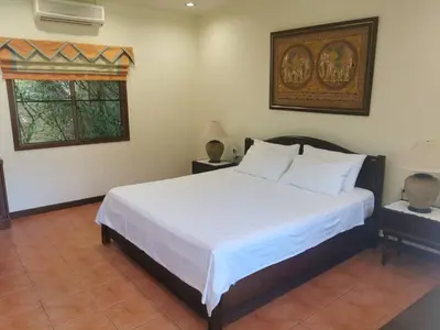 a bedroom with a bed with white sheets and a window at Villa Pimlada in Nai Harn Beach