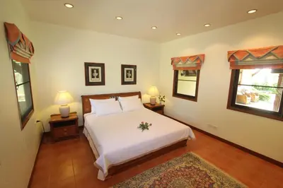 a bedroom with a white bed and two windows at Villa Pimlada in Nai Harn Beach