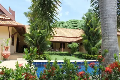 a house with palm trees and a swimming pool at Villa Pimlada in Nai Harn Beach