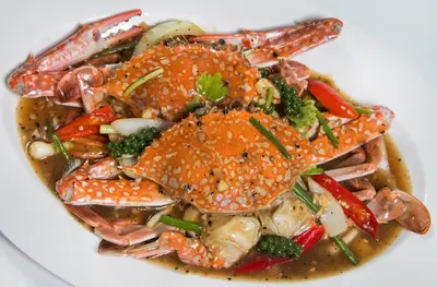 a white plate of food with crabs and vegetables at PS Hotel Phuket Patong - SHA Plus in Patong Beach