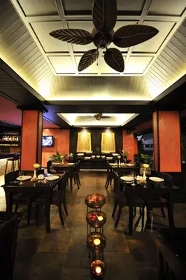 a restaurant with tables and chairs and a ceiling fan at Siralanna Hotel in Patong Beach