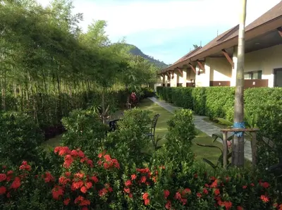 a garden with red flowers and a building with bushes at Aonang Glory Resort in Ao Nang Beach