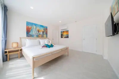 a white bedroom with a bed and a tv at Private sea view apartment with jacuzzi at Baycliff in Patong Beach