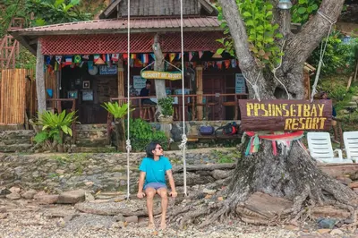 a woman sitting on a swing in front of a tree at Phi Phi Sunset Bay Resort in Phi Phi Don