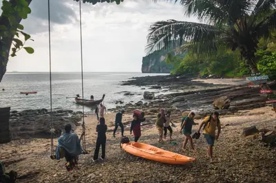 a group of people walking on a beach with a boat at Phi Phi Sunset Bay Resort in Phi Phi Don