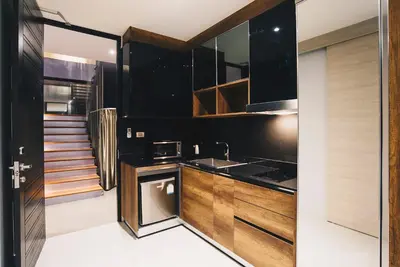 a kitchen with black walls and wooden cabinets at Searocco Phuket in Patong Beach