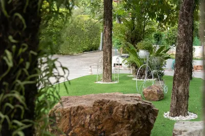 a garden with trees and a rock in the grass at Park 38 Hotel - SHA Plus in Phuket Town