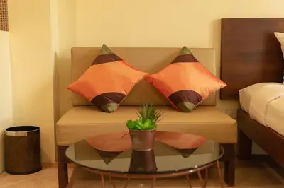 a couch with three pillows on it with a table at Park 38 Hotel - SHA Plus in Phuket Town