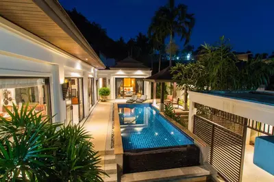 a villa with a swimming pool at night at Tulip Pool Villa Luxurious Villa Escape Awaits in Nai Harn Beach