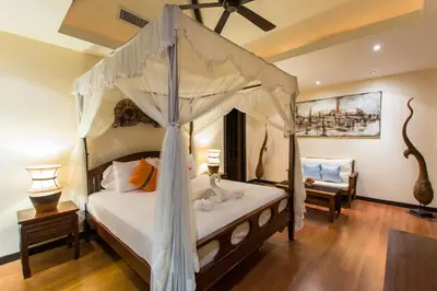 a bedroom with a canopy bed and a chair at Tulip Pool Villa Luxurious Villa Escape Awaits in Nai Harn Beach