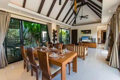 a dining room with a wooden table and chairs at Tulip Pool Villa Luxurious Villa Escape Awaits in Nai Harn Beach