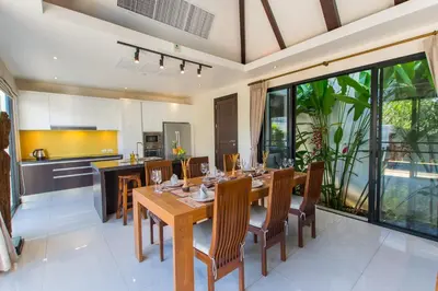 a kitchen and dining room with a wooden table and chairs at Tulip Pool Villa Luxurious Villa Escape Awaits in Nai Harn Beach