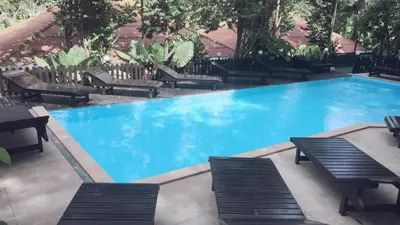 a large swimming pool with benches and a table and chairs at JJ Bungalow in Phi Phi Don